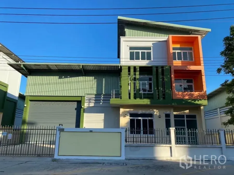 Factory for rent or sale in Lam Luk Ka, Pathum Thani - Full front elevation of the factory with colorful office facade and gated wall.