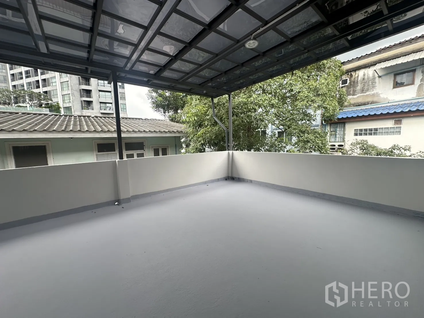 Home Office for rent in Khlong Toei, Bangkok - Roof terrace with metal canopy and neighborhood view.
