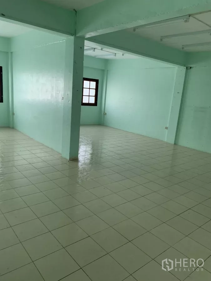 Shophouse for rent in Suan Luang, Bangkok - Open corner of a large tiled floor with a central support column and windows.
