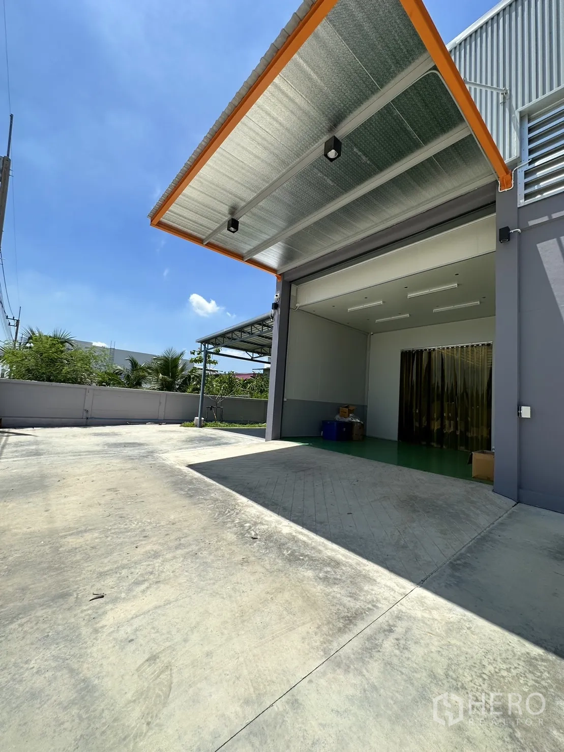 Factory for sale in Lam Luk Ka, Pathum Thani - Loading bay with wide roller door, canopy, and spacious concrete yard.