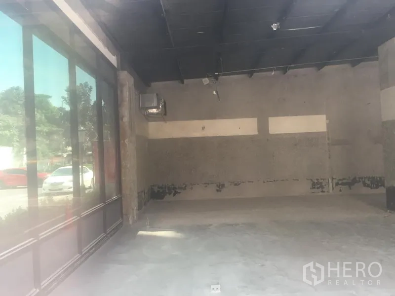 Retail Space for rent in Khlong Toei, Bangkok - Open-plan empty retail unit with high dark ceiling and unfinished concrete floor.