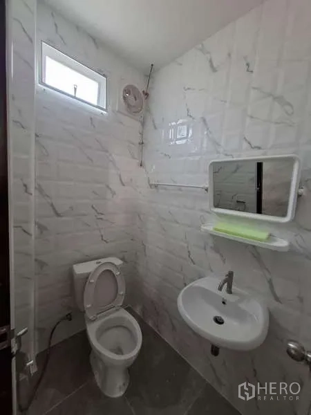 Warehouse for rent or sale in Bang Phli, Samut Prakan - Clean tiled bathroom with toilet, sink, mirror and ventilation window.