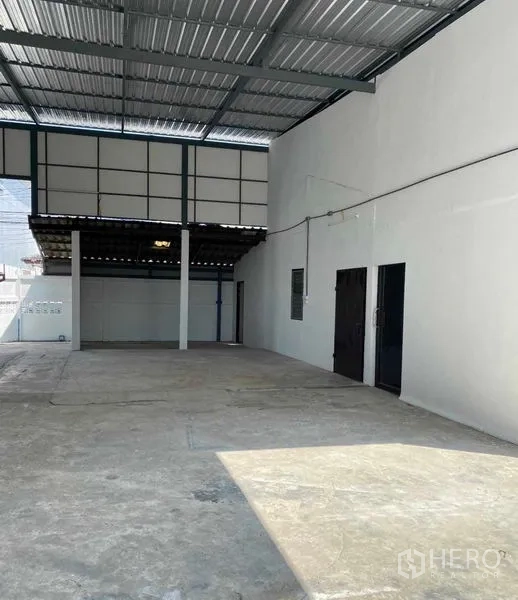 货栈 出租在Bang Khen, Bangkok - 仓库覆盖装卸区，钢结构高顶，混凝土地面与白色墙面，侧门可见