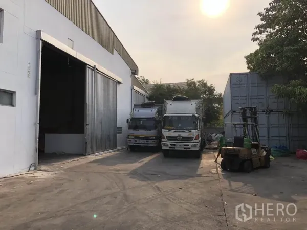 Factory for rent in Bang Bua Thong, Nonthaburi - Loading yard beside the factory with container trucks and forklift access in the afternoon light.