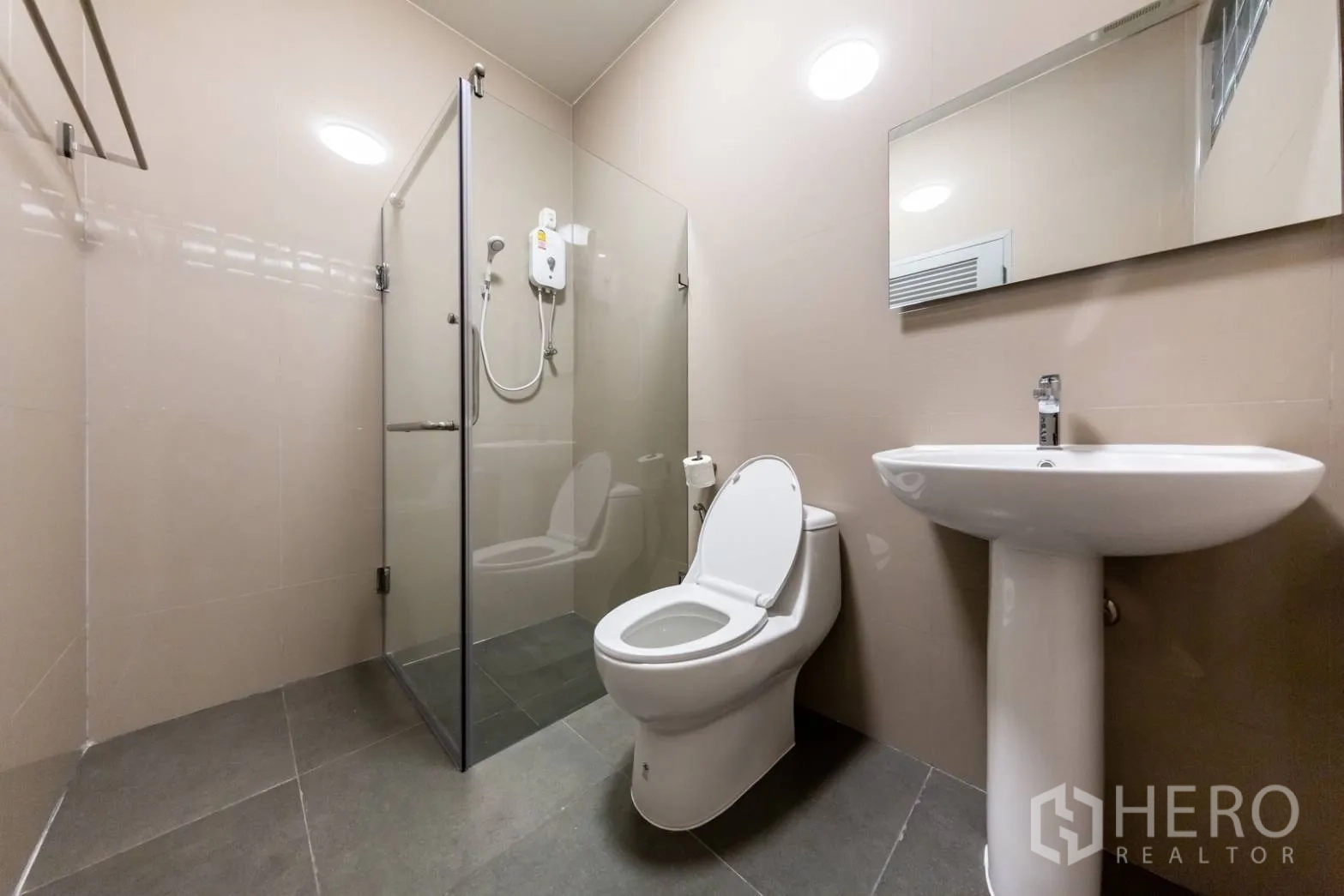 Home Office for rent in Bang Rak, Bangkok - Modern bathroom with glass shower enclosure, toilet and pedestal sink.