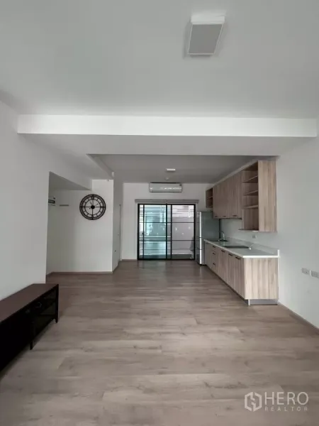 Townhouse for rent in Bang Phli, Samut Prakan - Open-plan living and dining area with wood floors, built-in kitchen, and sliding glass door.