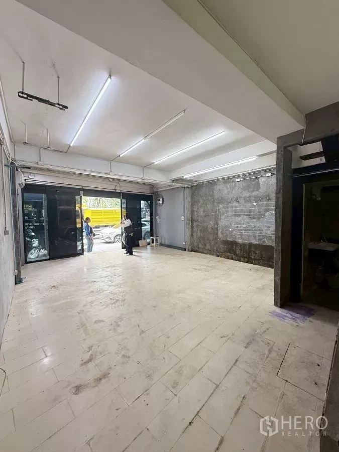 Shophouse for rent in Khlong Toei, Bangkok - Ground-floor retail space with wide glass storefront and bright fluorescent lighting facing the street.