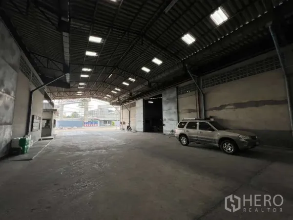 Warehouse for rent in Pak Kret, Nonthaburi - Covered loading area inside the warehouse with roller shutter doors, skylights and vehicle access.