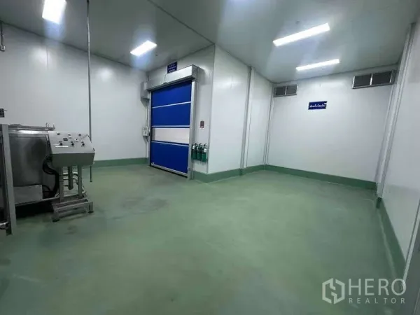 Factory for rent - Cleanroom loading area featuring a blue high-speed roll-up door, epoxy flooring, and wall-mounted fire extinguishers.