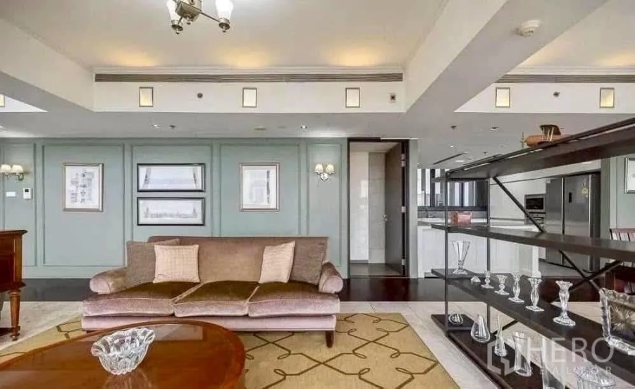 Condominium for rent in Sathon, Bangkok - Elegant living room with plush sofa, open shelving and a view toward the modern kitchen in a high-floor condo at The Met.