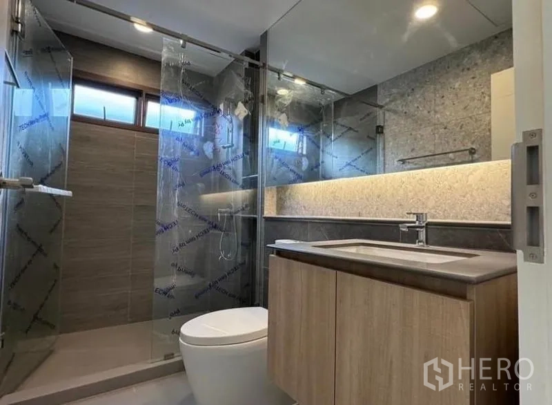 Detached House for rent in Bang Kapi, Bangkok - Bathroom with sliding glass shower door and stone-textured backsplash.