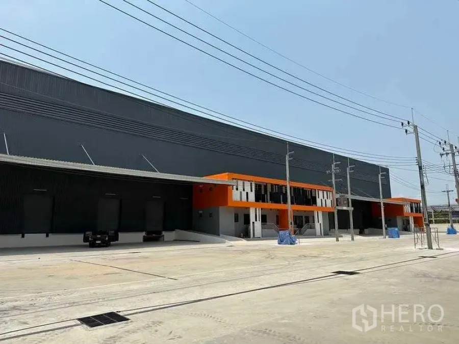 Factory for rent in Bang Phli, Samut Prakan - Modern Free Zone factory exterior with long loading bays, orange-accented office block and wide concrete yard in Bang Phli.