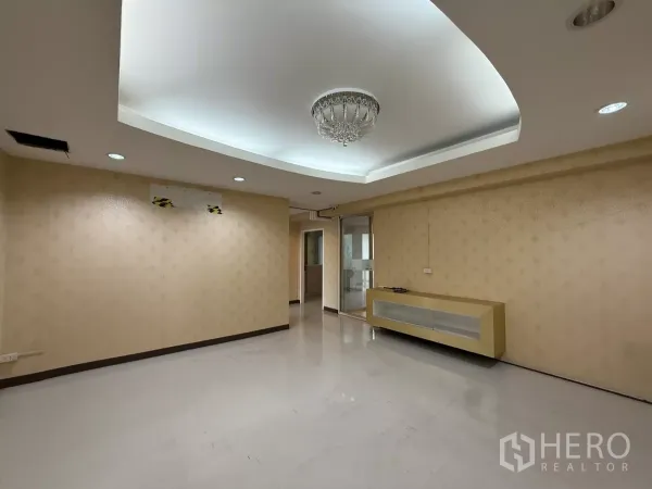 Office Space for rent in Din Daeng, Bangkok - Large open office with recessed coffered ceiling, chandelier, beige walls and a floating cabinet.