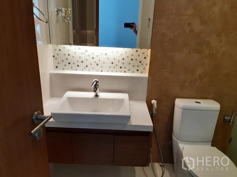 Condominium for rent or sale in Khlong Toei, Bangkok - Guest bathroom with square basin, backlit mirror and toilet.