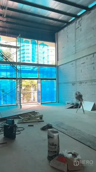 Retail Space for rent in Khlong Toei, Bangkok - Open-plan unit showing tall storefront glazing, scaffolding and unfinished flooring.