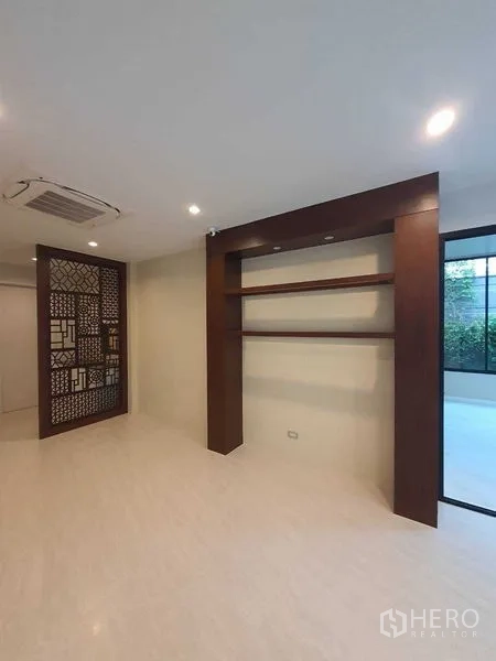 Detached House for sale in Prawet, Bangkok - Family room with wooden shelving, feature screen, and access to the garden.