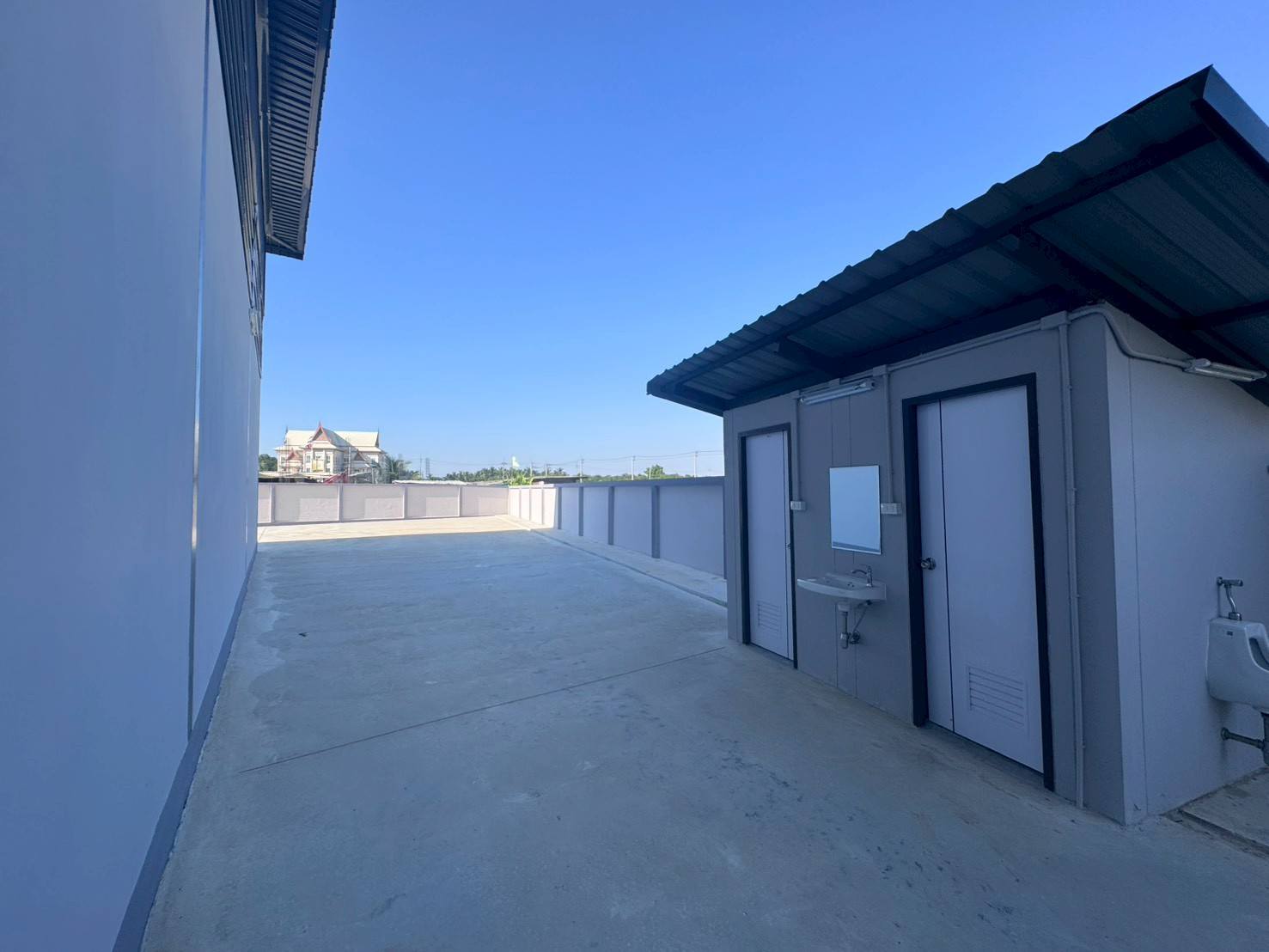 Factory for sale in Mueang Samut Sakhon, Samut Sakhon - Outdoor service area with separate restroom block, sink and spacious concrete walkway.
