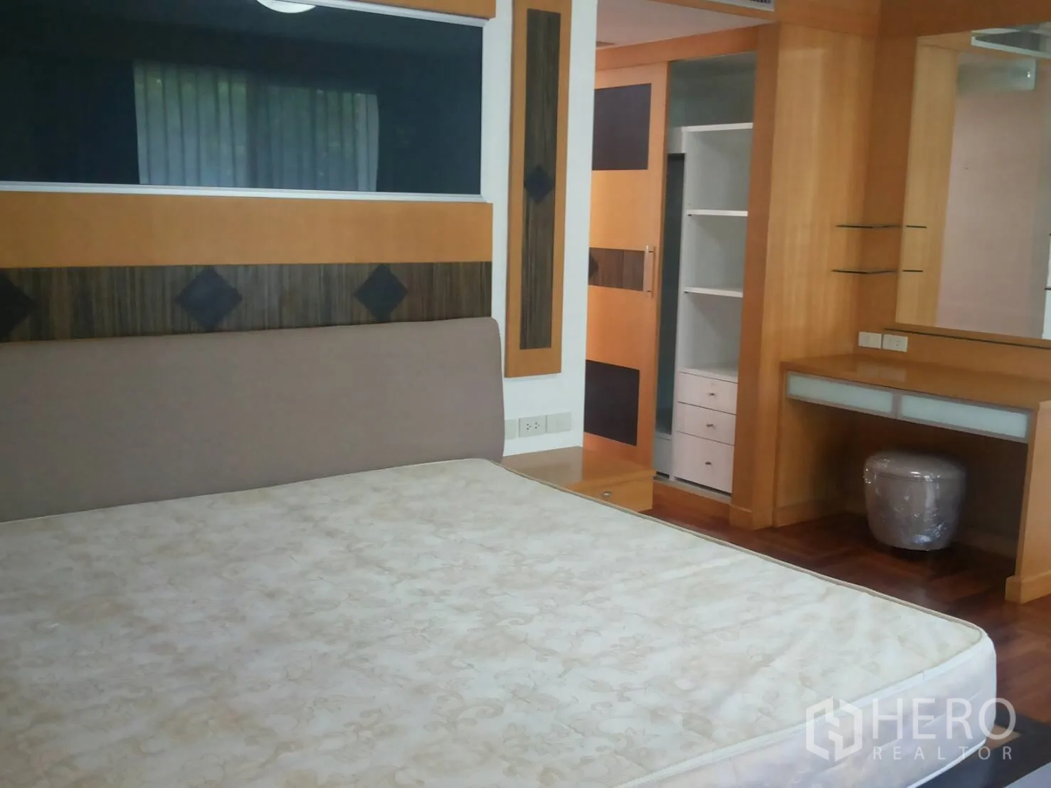 Apartment for rent in Khlong Toei, Bangkok - Master bedroom with built-in wardrobe, dressing table, and warm wood accents.
