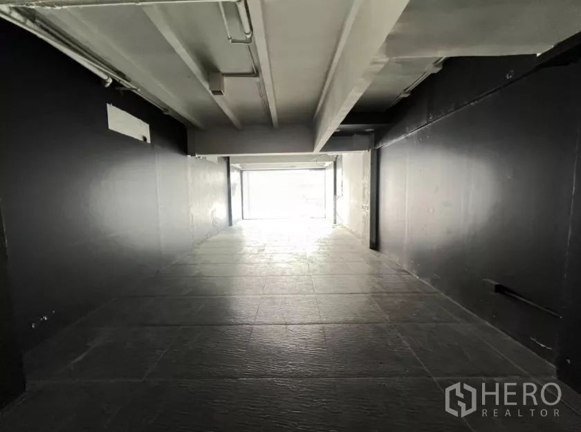 Retail Space for rent in Watthana, Bangkok - Deep retail unit with black walls, overhead lights, and textured tile floor.