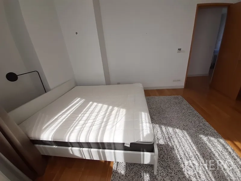 Condominium for rent in Khlong Toei, Bangkok - Master bedroom view toward doorway with wood floors and area rug.