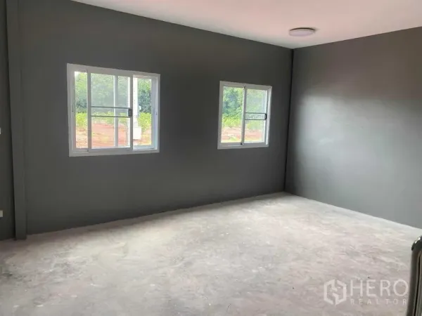 Warehouse for rent in Bang Bon, Bangkok - Bright office room with two sliding windows, gray walls and a concrete floor.