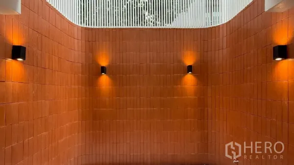 带办公室的家 出租在Watthana, Bangkok - 弧形红陶天井墙，现代壁灯与上方开口采光。