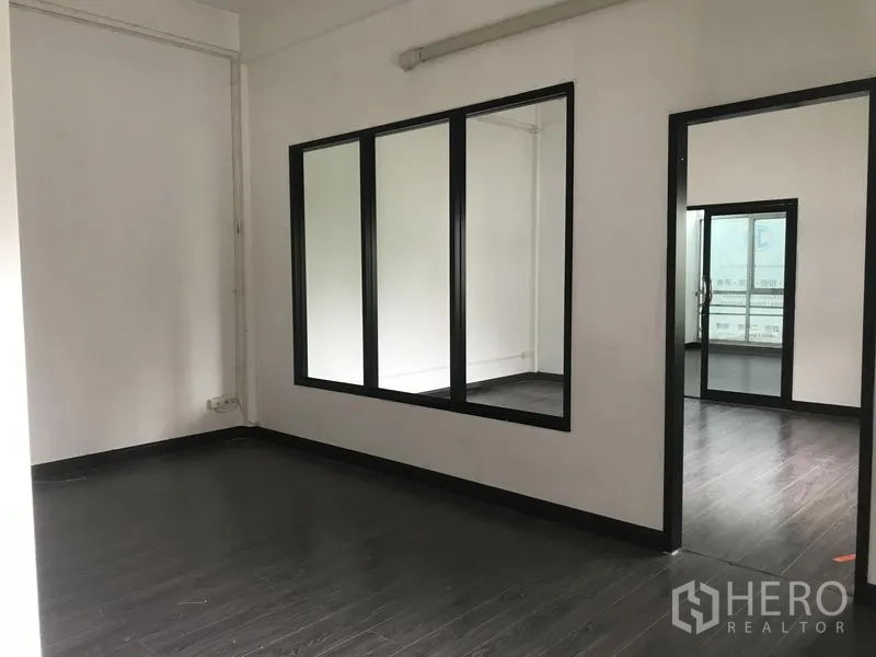 Shophouse for rent in Watthana, Bangkok - Office-style room with a large internal glass window and doorway to a meeting area.