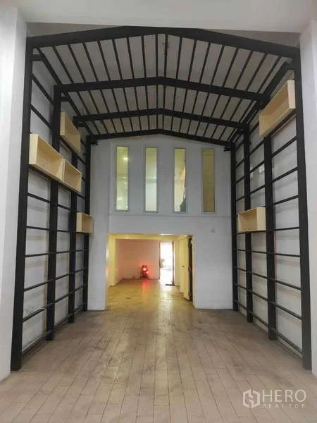 Shophouse for sale in Phra Khanong, Bangkok - High-ceiling shophouse hall with black steel beams and mezzanine windows.