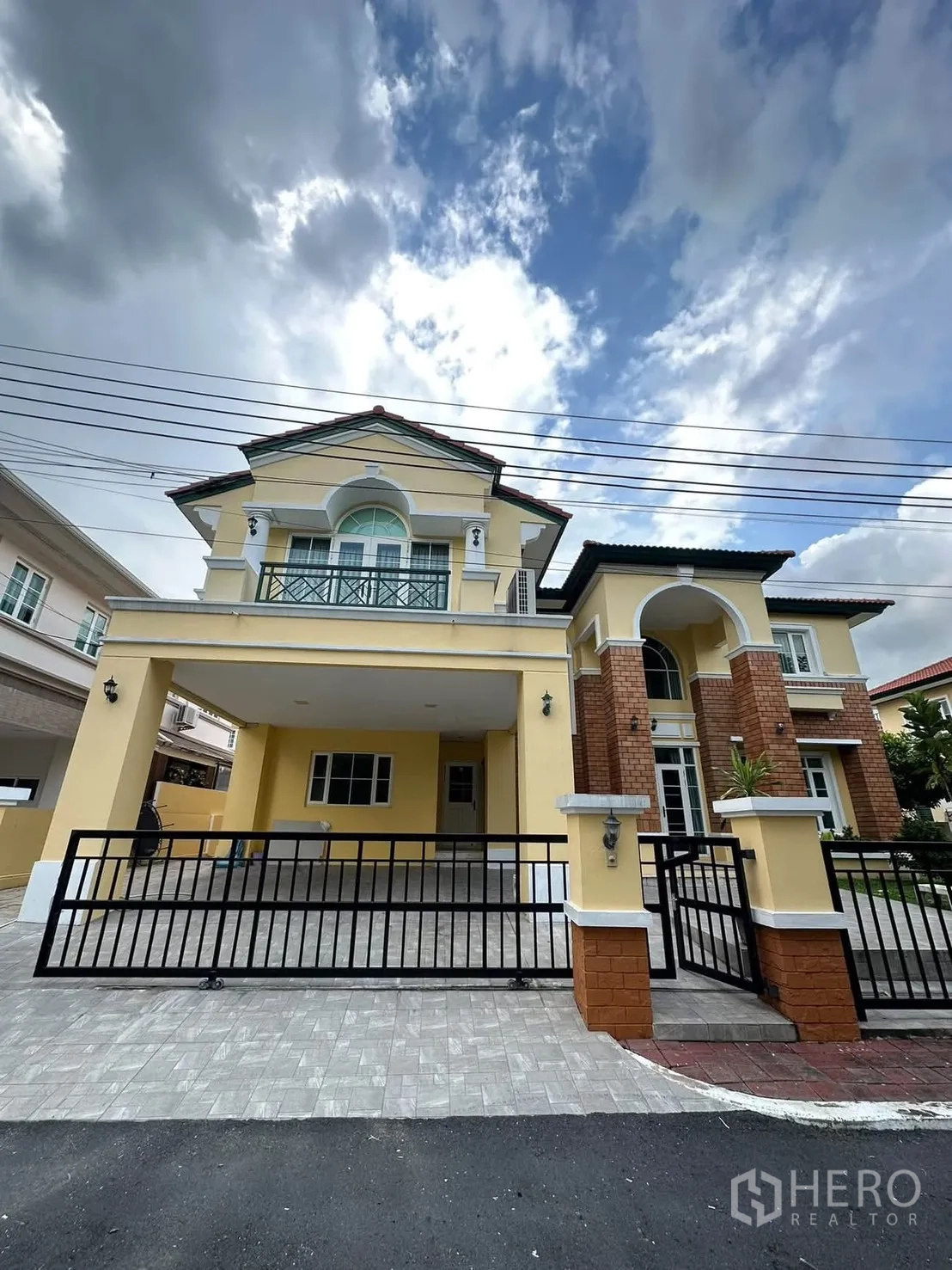 Detached House for rent in Phra Khanong, Bangkok - Front exterior of a two-storey house with brick accents, covered carport, and gated driveway.