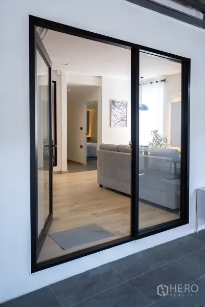 Detached House for rent in Huai Khwang, Bangkok - Close view of black-framed sliding door opening to a bright living room.