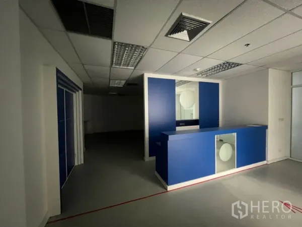 Office Space for rent - Reception area with a blue counter and overhead fluorescent lighting.