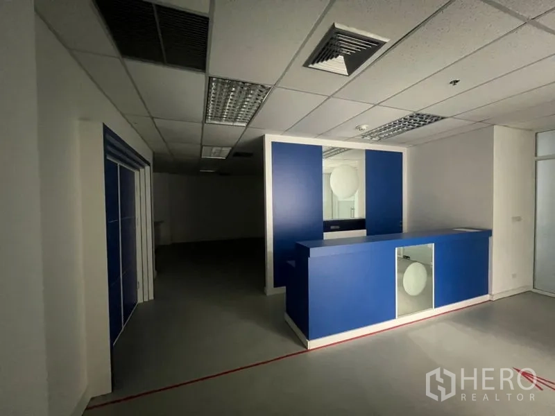 Office Space for rent - Reception area with a blue counter and overhead fluorescent lighting.