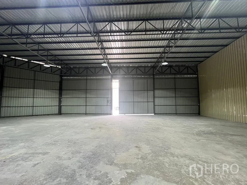 Warehouse for rent in Phra Khanong, Bangkok - Interior facing the main doors with metal-clad walls and a trussed roof structure.