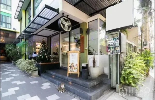 Shophouse for rent in Bang Rak, Bangkok - Glass-front shophouse facade with covered entry, signage space and planters along a pedestrian lane in Bang Rak.