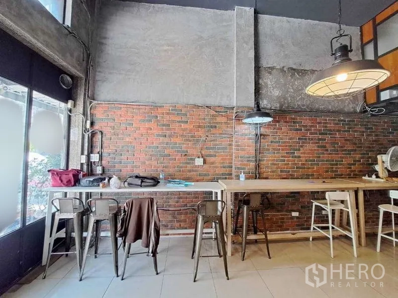 Retail Space for rent in Khlong Toei, Bangkok - Bar-height seating along an exposed brick wall under hanging lights beside the front windows.