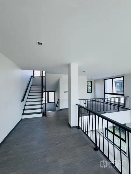 Home Office for sale in Bang Khen, Bangkok - Open mezzanine level overlooking the atrium with metal balustrade and connecting staircase.