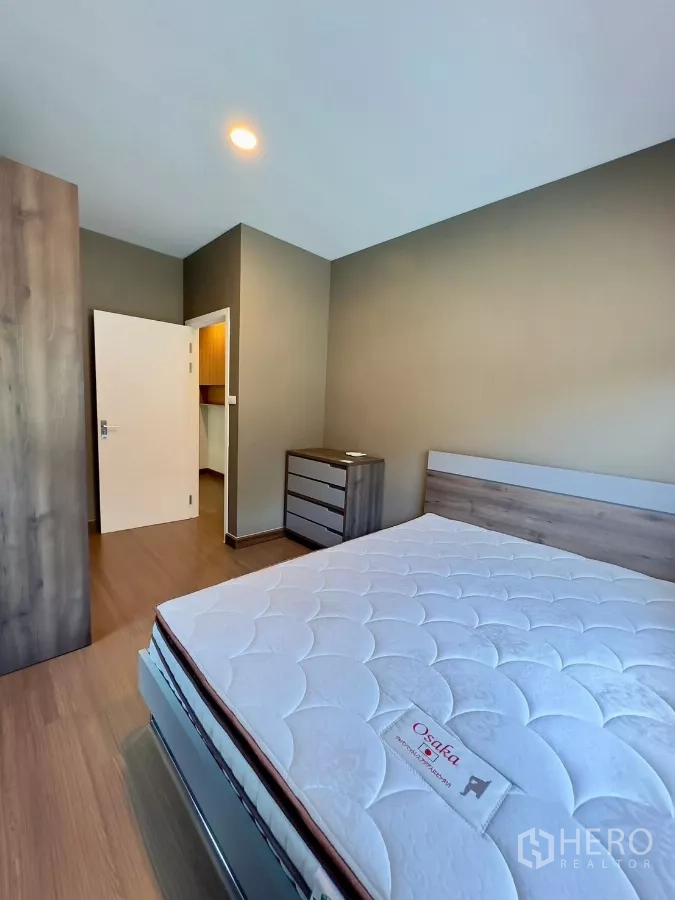 Detached House for rent in Samut Prakan - Bedroom angle showing mattress, wardrobe and doorway to the hall.