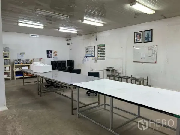 Warehouse for rent in Sam Phran, Nakhon Pathom - Preparation area with long stainless worktables, shelving and a whiteboard.