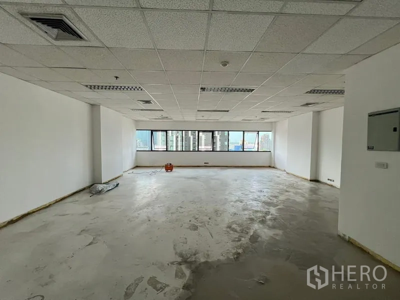 Office Space for rent in Watthana, Bangkok - Open-plan 76 sqm office with grid ceiling, fluorescent lighting, and wide city-view windows near Ekkamai.