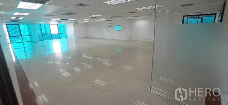 Office Space for rent in Huai Khwang, Bangkok - Spacious office floor with glass partition, tiled flooring and blue-tinted windows bringing natural light.