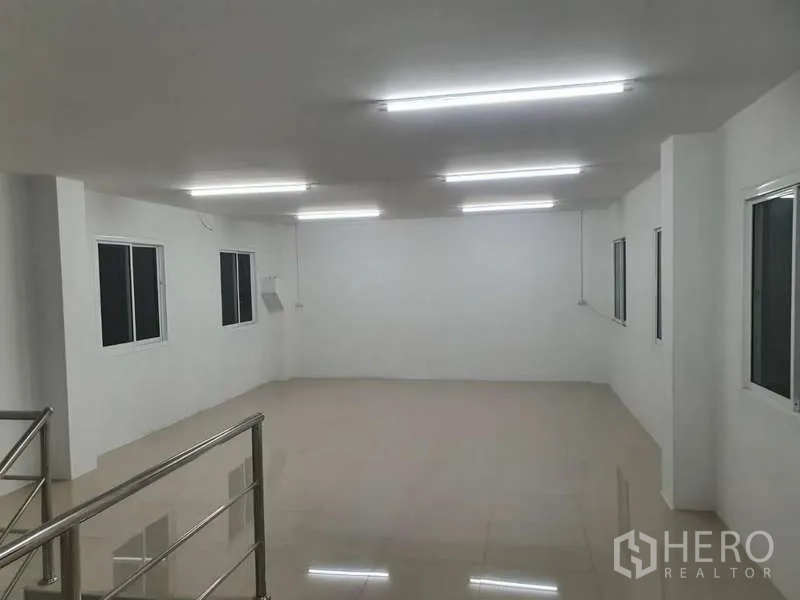Warehouse for rent in Khlong Luang, Pathum Thani - Bright upper-floor office with tiled floors, windows and fluorescent lighting overlooking the warehouse.