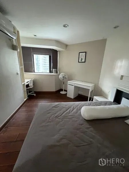 Condominium for rent - Bedroom study nook with desk by the window, wall-mounted AC and wood floors.