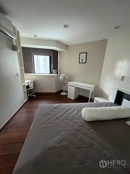 Condominium for rent - Bedroom study nook with desk by the window, wall-mounted AC and wood floors.