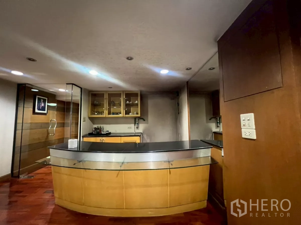Shophouse for rent in Bang Rak, Bangkok - Built-in bar counter with wood cabinetry and glass display on an upper floor.