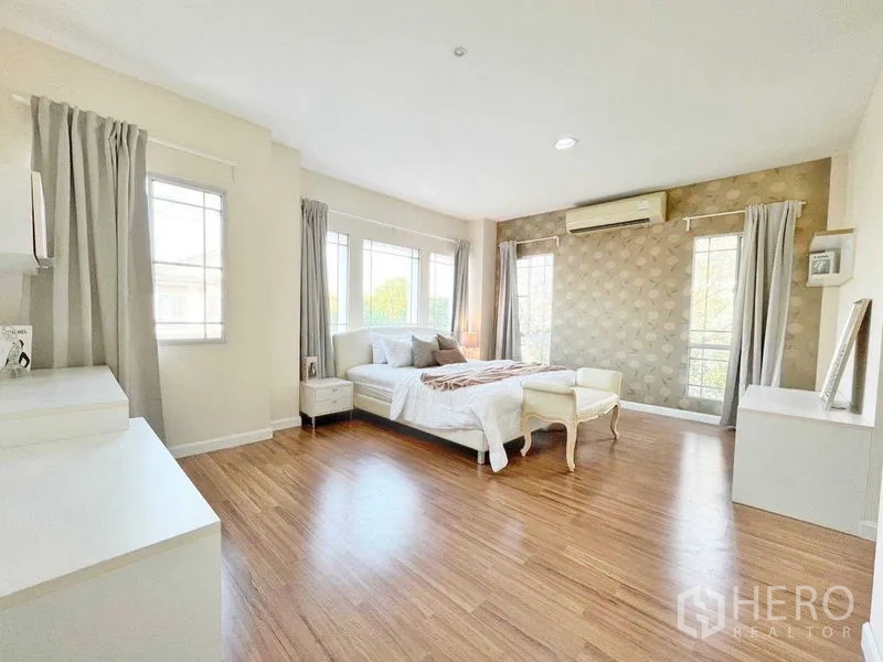 Detached House for rent in Prawet, Bangkok - Large corner bedroom with wood floors, multiple windows, bed and air conditioning.