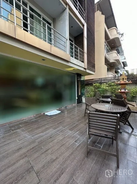 房间 出租在Khlong Toei, Bangkok - 一层露台设有户外桌椅与绿植，紧邻建筑外墙。
