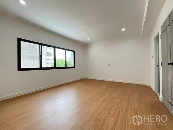 联排别墅 出售在Watthana, Bangkok - 宽敞卧室，横向大窗与嵌灯，木纹地板