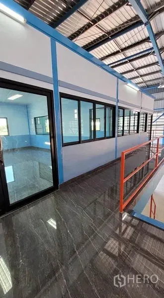 Factory for rent or sale in Phanat Nikhom, Chon Buri - Second-floor glass office and corridor with glossy tile flooring and an orange safety handrail inside the factory.