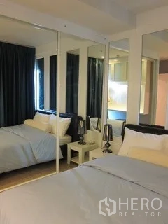 Condominium for rent in Khlong Toei, Bangkok - Cozy bedroom with mirrored wardrobe, dark curtains and bedside lamps.
