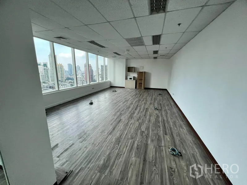 Office Space for rent in Watthana, Bangkok - Bright unfurnished office with wood-look flooring, drop ceiling, and full-height windows overlooking the Bangkok skyline.